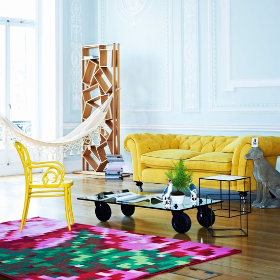 gelber Sofa bunter lila Teppich Wohnzimmer