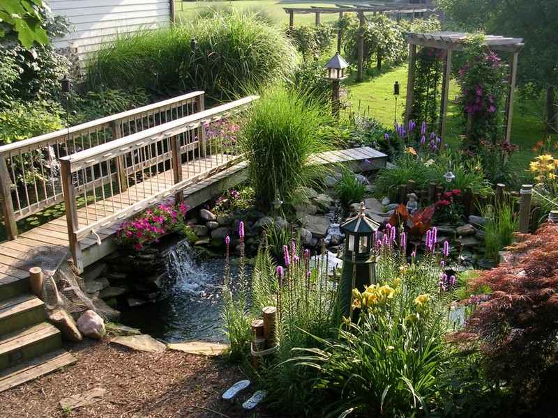 Gartenteich bauen Wasserspiele-Bruecke-Holz-Blumen