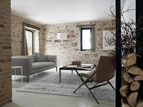 rustikales Wohnzimmer Natursteinwand graues Sofa  Holz helle Farben