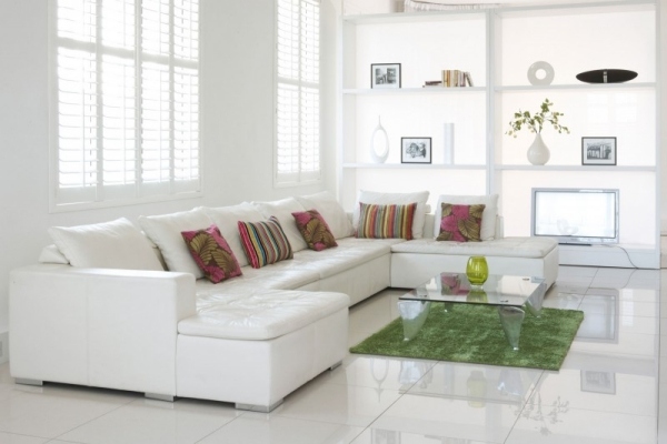 weißes wohnzimmer einrichtung bunte kissen grüner teppich glastisch