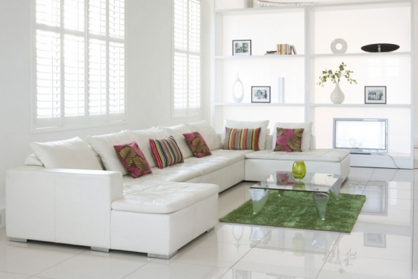 white-sofa-with-colorful-cushion-and-green-rug-under-glass-table