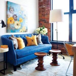 kleines schmales Wohnzimmer einrichten Ideen blauer Sofa Gemälde Wand Holz Stühle-Deko-Kissen-gelb