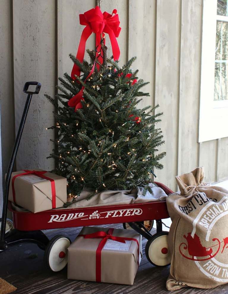 Weihnachtsdeko Terrasse Weihnachtsbaum in Bollerwagen und Geschenke verzieren