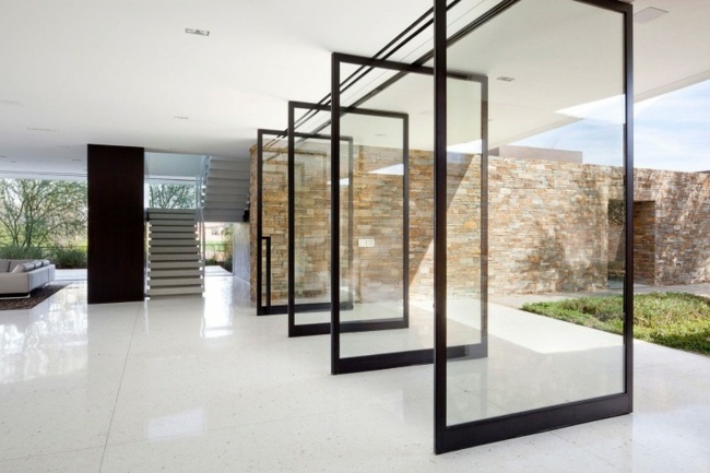 Glastür Fassade Steinfliesen Bodenplatten offener Wohnbereich