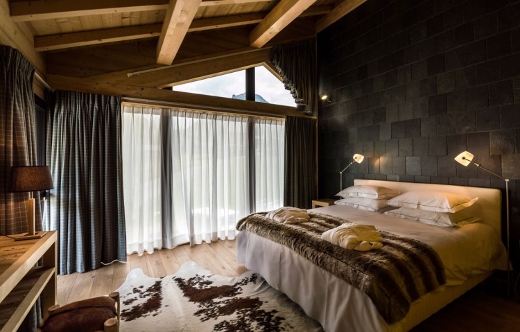 schlafzimmer-einrichtung-stil-chalet-modern-steinwand-schwarz-holztraeger-fellteppich-terrassentueren