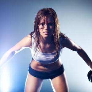 frau blau hintergrund licht sportlich angezogen gewichte heben arm trainieren