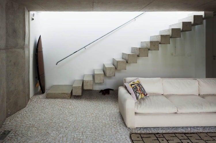 moderne-betontreppe-bauen-minimalistisch-couch-cremeweiss-licht-pflaster-handlauf-metall