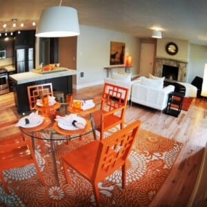 wohnkueche-essbereich-orange-stuehle-teppich-blumenmuster-wohnzimmer-kamin