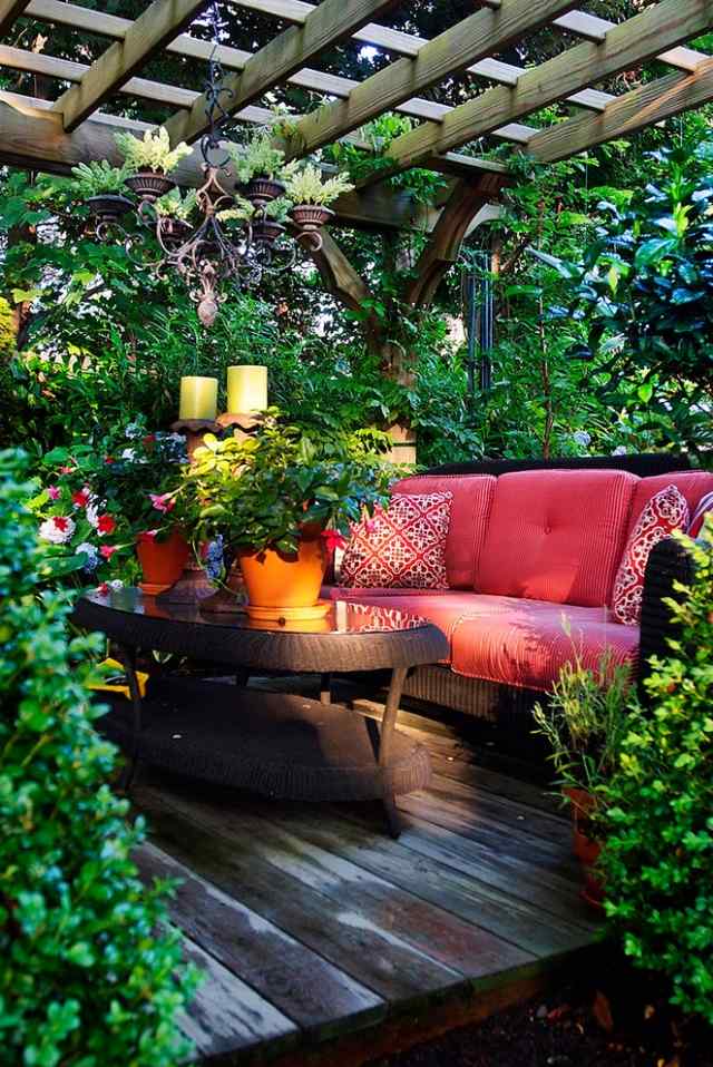 holz pergola im garten grünpflanzen sichtschutz sofa rattan rosa kissen