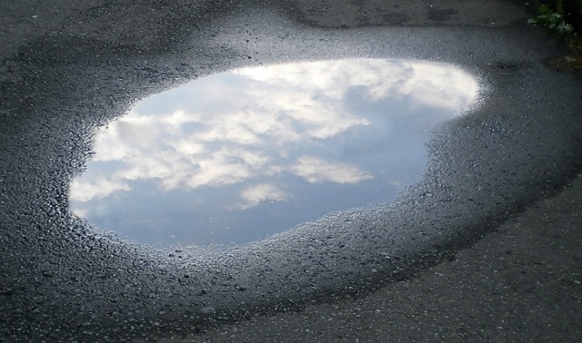 Wasser Pfütze im asphalt reflektiert Himmel
