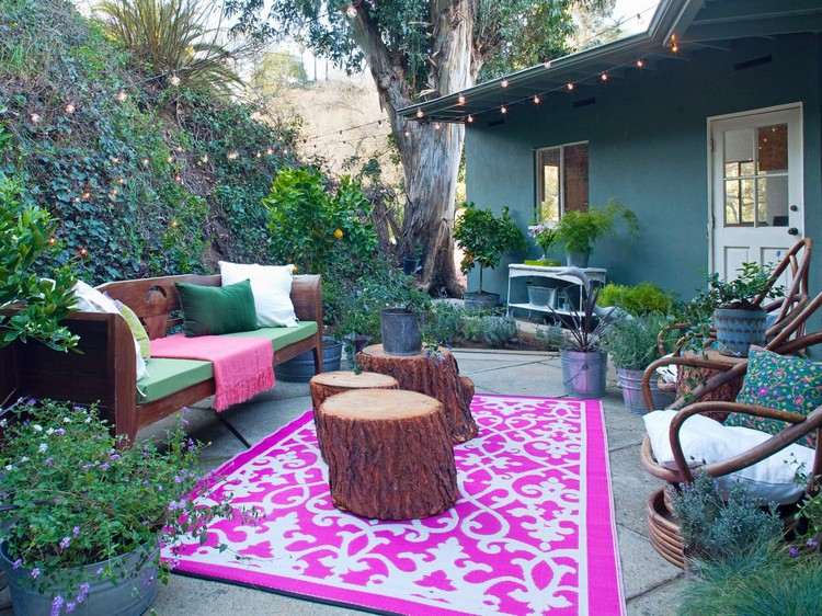Gartenterrasse im Bohemian-Style steinplatten-bodenbelag-pinker-outdoor-teppich-baumstamm-beistelltische