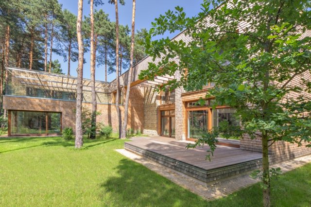 Luxus Villa Stein Holz verkleidet Rasen Bäume Eiche