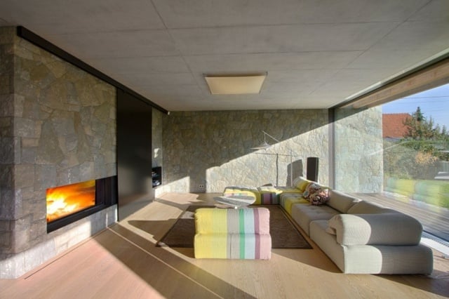 Steinwand Laminatboden Sofa bunter Sessel Kamin Glasfronten
