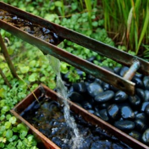 Metall Gartenbrunnen Wasserspiele Flusssteine niedrige Vegetation