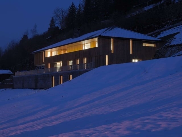 modernes ferienhaus verschneite hügel nachtbeleuchttung friborg schweizer alpen