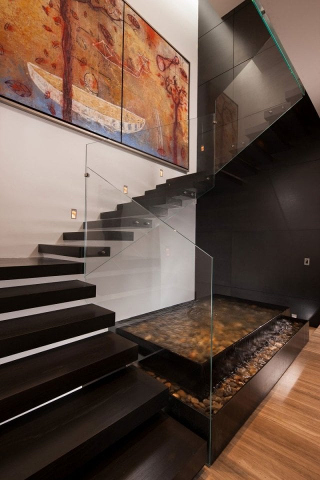 halbgewendelte treppe modern holzstufen glas geländer wasserspiel kies