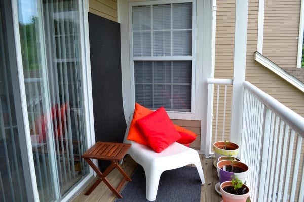 kleine-städtische-balkone-einrichten-teppichboden-Weißer-Sessel-Rot-Kissen