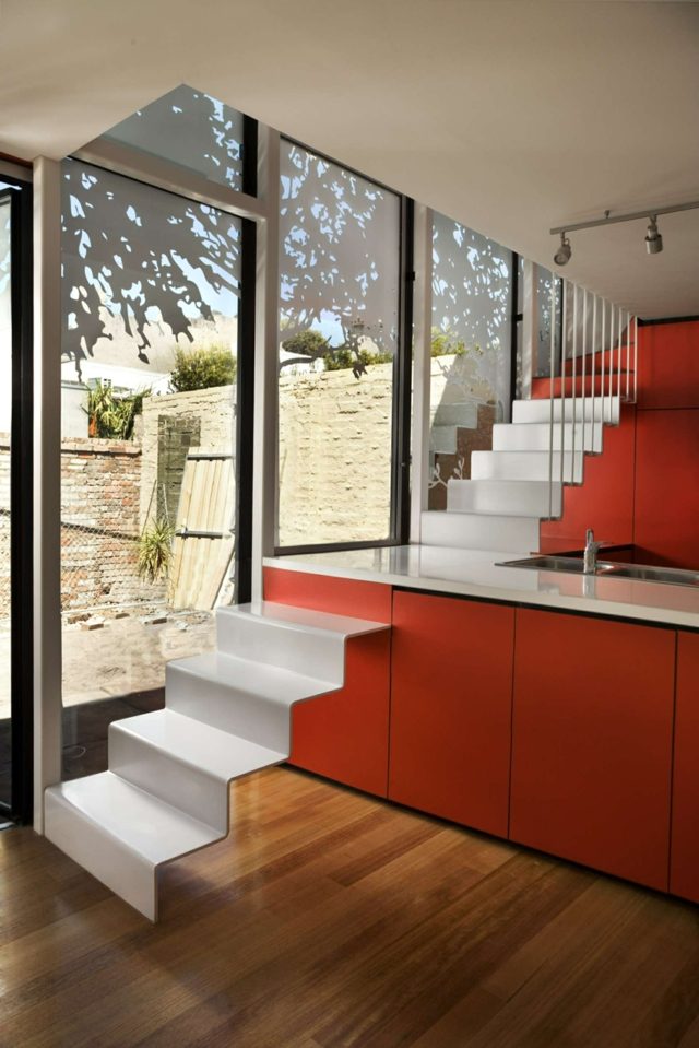 moderne Küche Treppe integriert rote Küchentheke Glasfronten Holz Boden