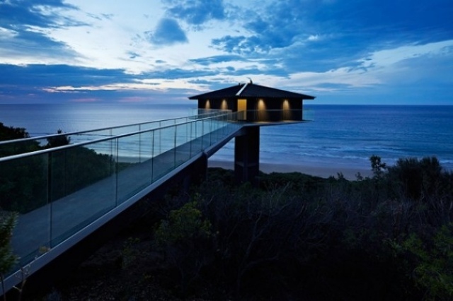 Modernes-Haus-überblickt-die-Küste-erreichbar-über-eine-Brücke