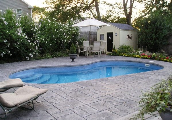 Haus-mit-Garten-Steinboden-Sonnenschirm-Poolbereich