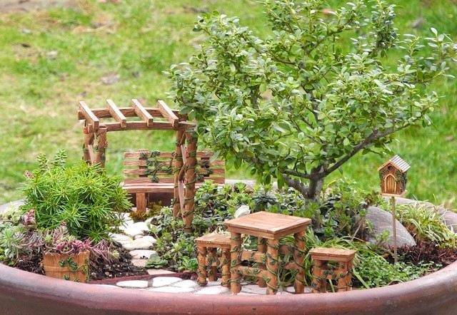 Pflanztopf dekorieren Gartenbank Holztisch Stühle kleiner Zierbaum