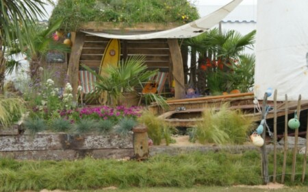 Strandfeeling schöne Gartendeko Ideen Surfboard Sonnensegel Gartenhaus mediterrane Blumen