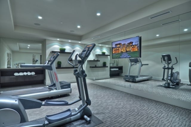 heim-fitnessstudio-einrichten-modern-grauer-teppichboden-einbauleuchten-fernseher-spiegelwand