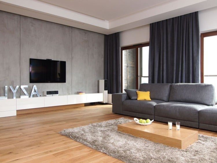 Schoene-einrichtungsideen-wohnzimmer-fernseher-betonwand-grau-holzboden-couchtisch-holzblock
