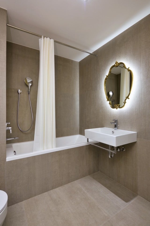 kleines-bad-feinsteinzeug-fliesen-braun-badewanne-duschvorhang-spiegel-hinterbeleuchtung