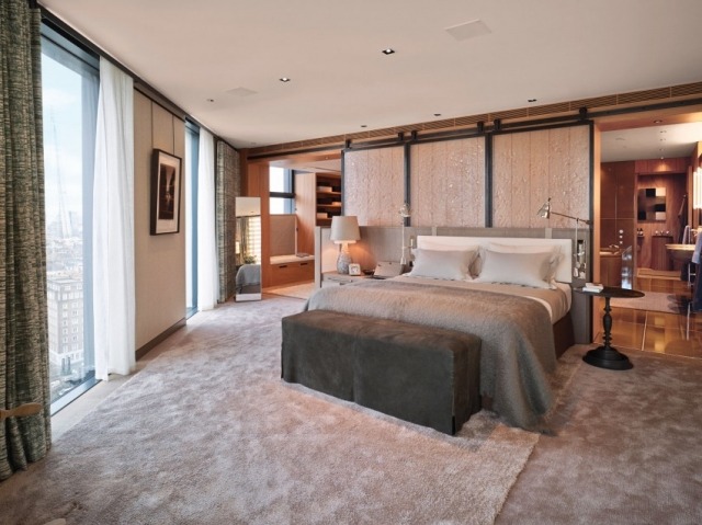 modernes-schlafzimmer-fensterfront-graues-bett-beige-teppichboden-schiebetueren-badezimmer