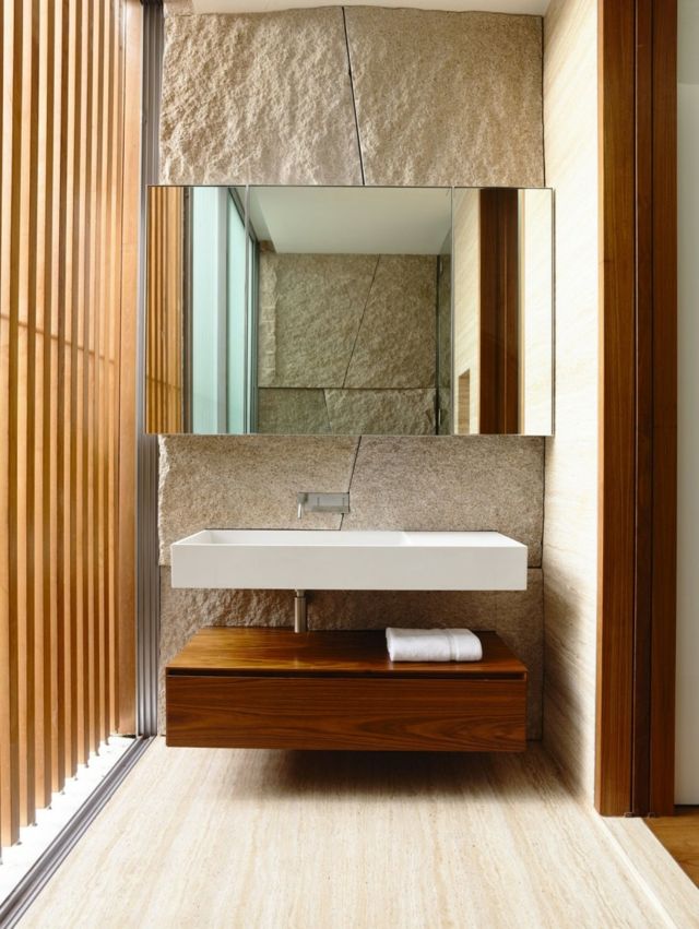 Wand-aus-grobem-Naturstein-Raumteiler-mit-Holzstäben