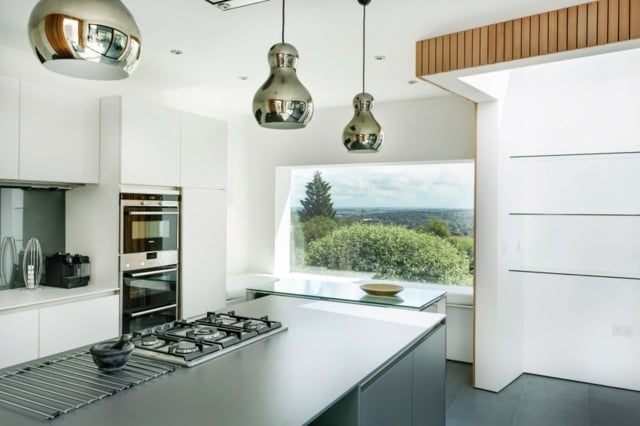 Widerspiegelnde-Pendelleuchte-Kücheninsel-mit-Gaskochplatte-Blick-in-den-Wald