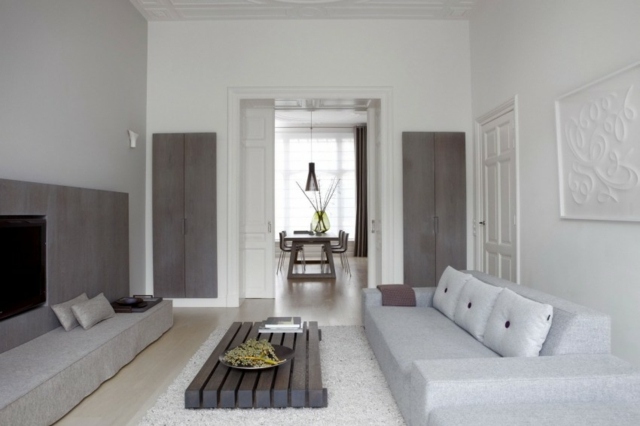 hohe-Zimmerdecke-helle-graue-Polsterung-Holztisch-und-eingebaute-Wandschränke