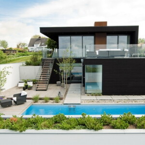 Einfamilienhaus Pool Holzterrasse niedrige Sträucher Betonmauer