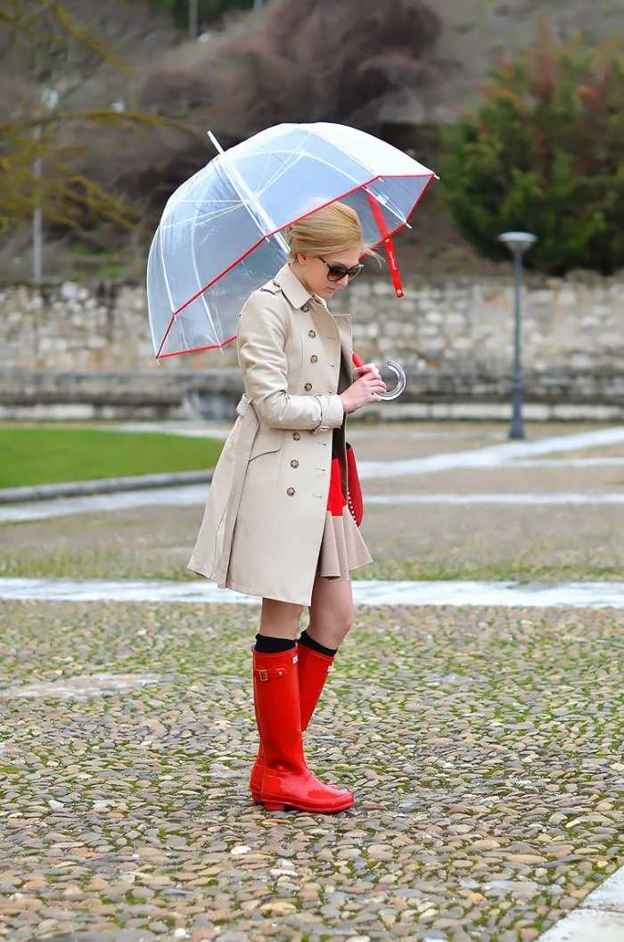 kräftig-rote-Regenstiefel-beige-farbener-Mantel-transparenter-Regenschirm-street-style