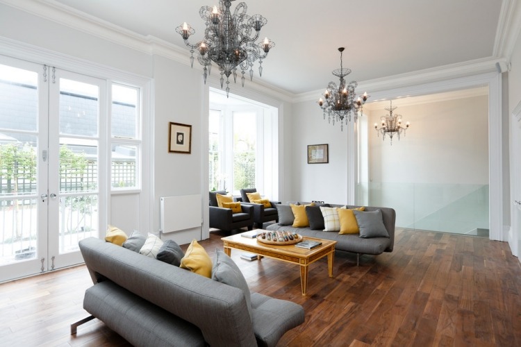 modernes-wohnzimmer-grau-gelb-holzboden-schwarze-metall-kronleuchter