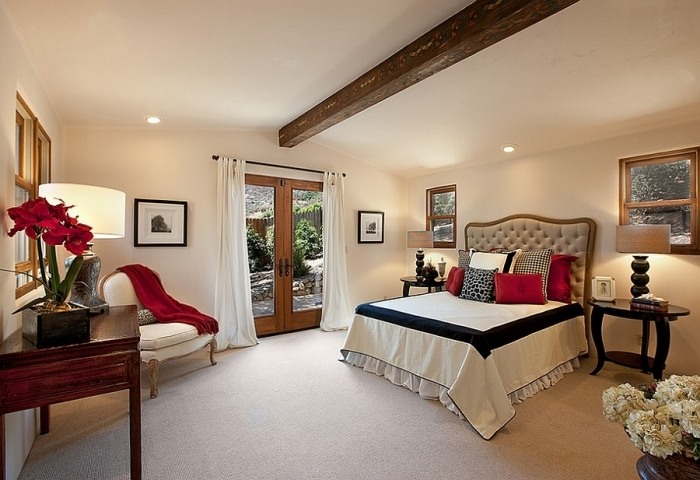 elegantes-schlafzimmer-rote-akzente-sichtbare-deckenbalken-teppich-cremefarben