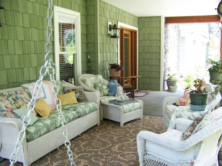 überdachte-terrasse-gestalten-wie-wohnzimmer-flechtmöbel-weiß-florale-auflagen-grüne-wand