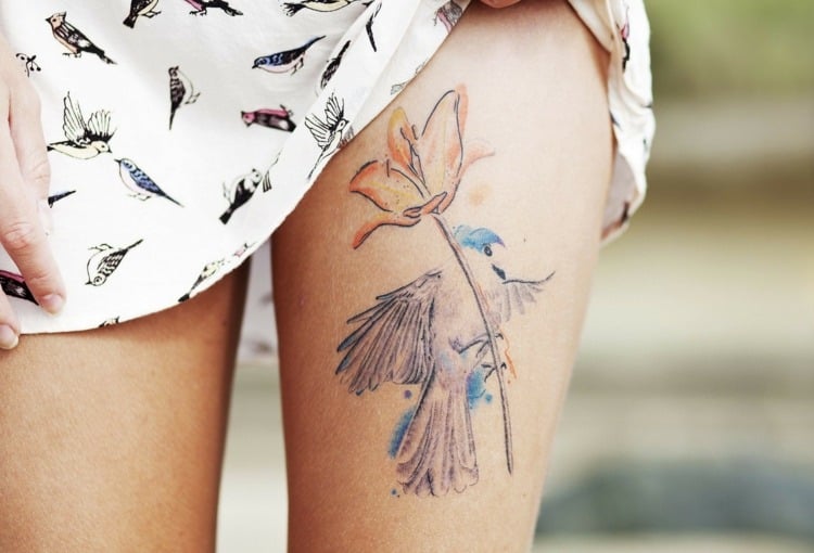 tattoo motive oberschenkel-dezent-farben-vogel-blume-minimalistisch-künstlerisch