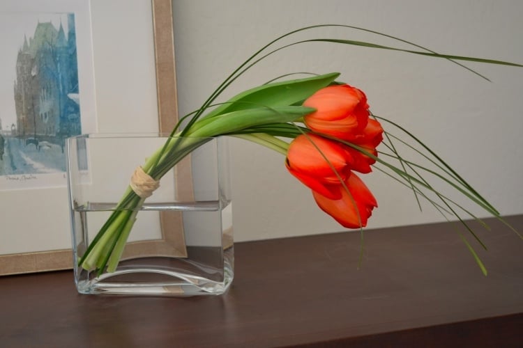fruehlingsdeko-rote-tulpen-rechteckige-glasvase-gras