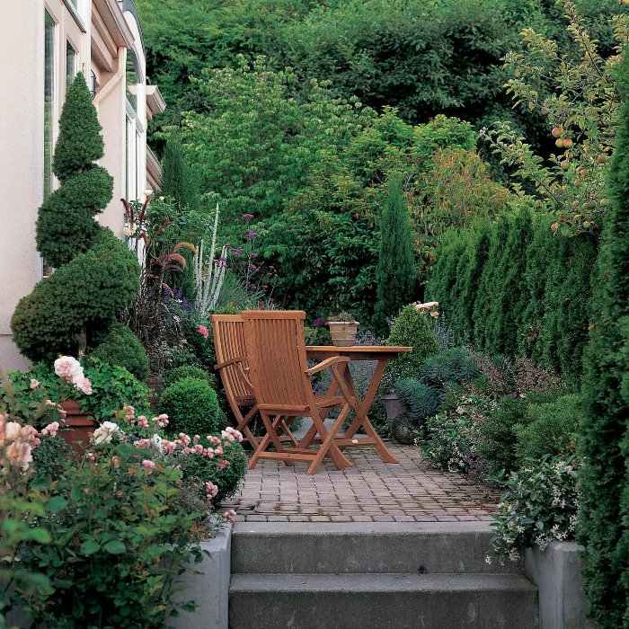 kleine terrasse sichtschutz grüne hecke wilde gartengestaltung stuhl holz