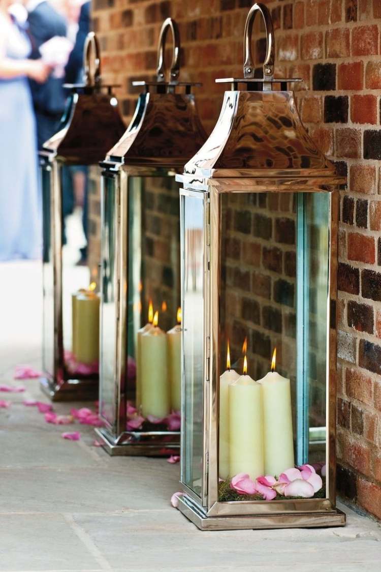 Gartenlaternen mit Kerzen -metal-gross-ziegelwand-draussen-rosenblaetter-romantisch