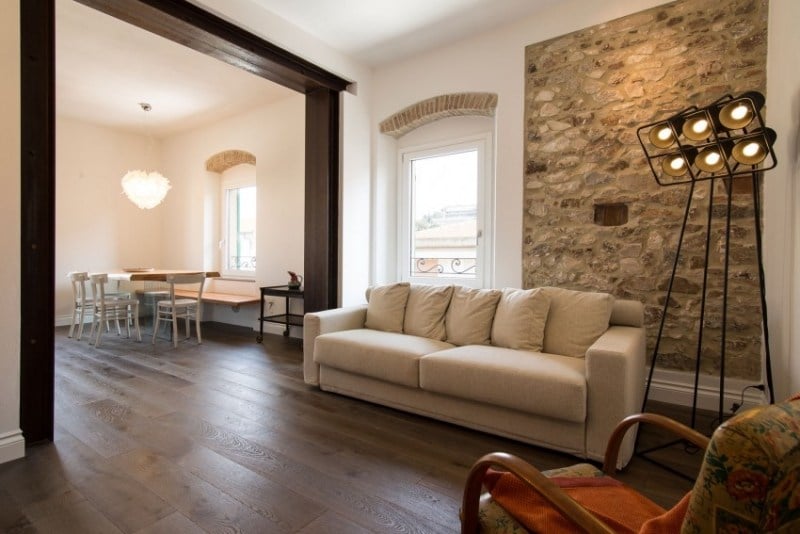 einrichtung-wohnzimmer-alt-neu-stilmischung-couch-grau-sessel-antik-leuchte-steinwand-weiss-putz