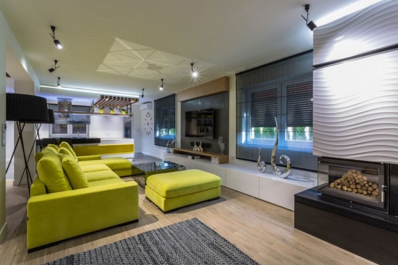 einrichtung-wohnzimmer-senfgelb-sofa-polster-kaminofen-tvwand-beleuchtung-teppich-grau