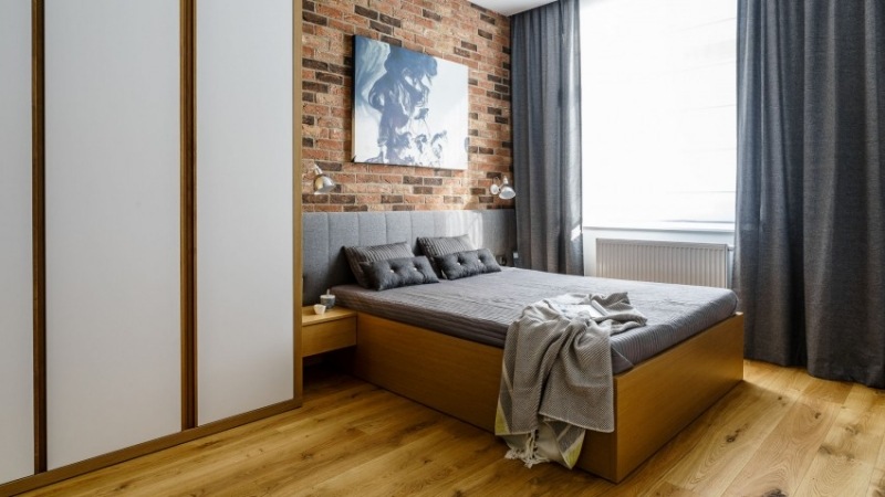 moderne-schlafzimmer-rote-backsteinwand-holzboden-graue-gardinen-bettkopfteil