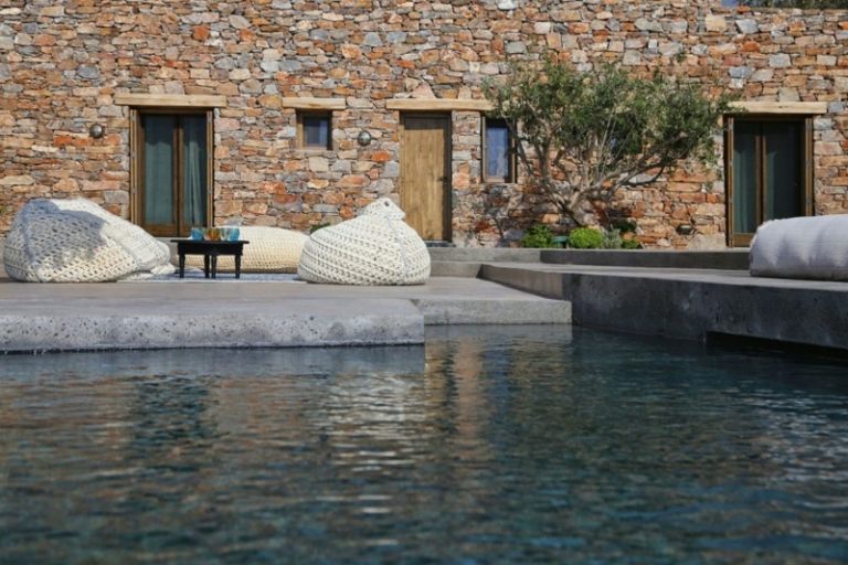 stein fassade weisser haus terrasse sitzsaecke pool design rustikal
