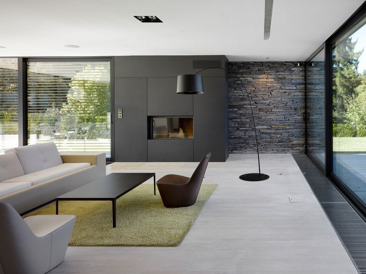 neue-wohntrends-wohnzimmer-glaskamin-schwarze-wandpaneele-steinwand-gruener-teppich