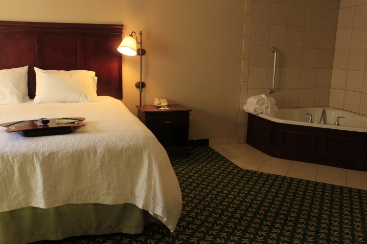 schlafzimmer-whirlpool-hotelzimmer-teppichboden-nachtlampe-bett-betwaesche-kissen