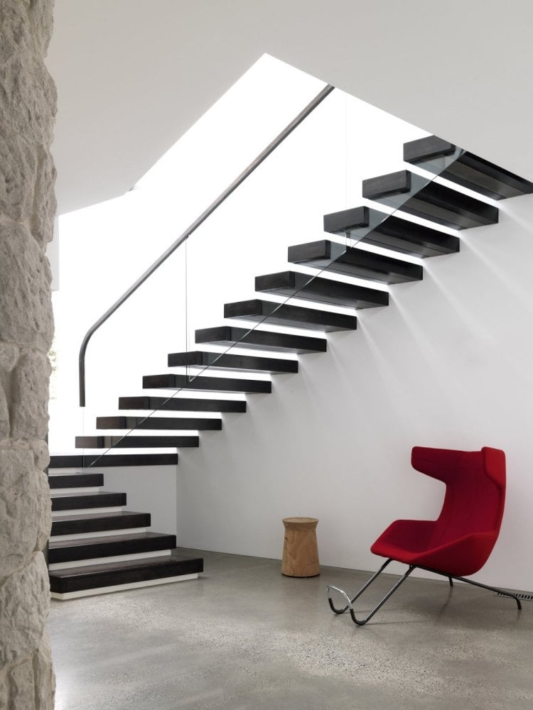 schwebende-treppen-schwarz-weiss-treppenhaus-modern-sessel-rot-hanlauf-edelstahl-gelaender-glas-wand
