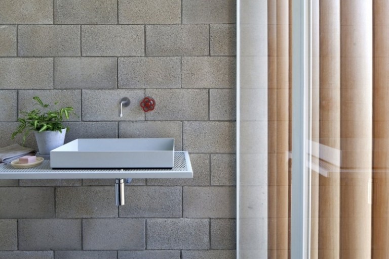 sichtbeton-innen-waschbecken-minimalistisch-ziegelwand-grau-fensterwand-holzlamellen-vertikal